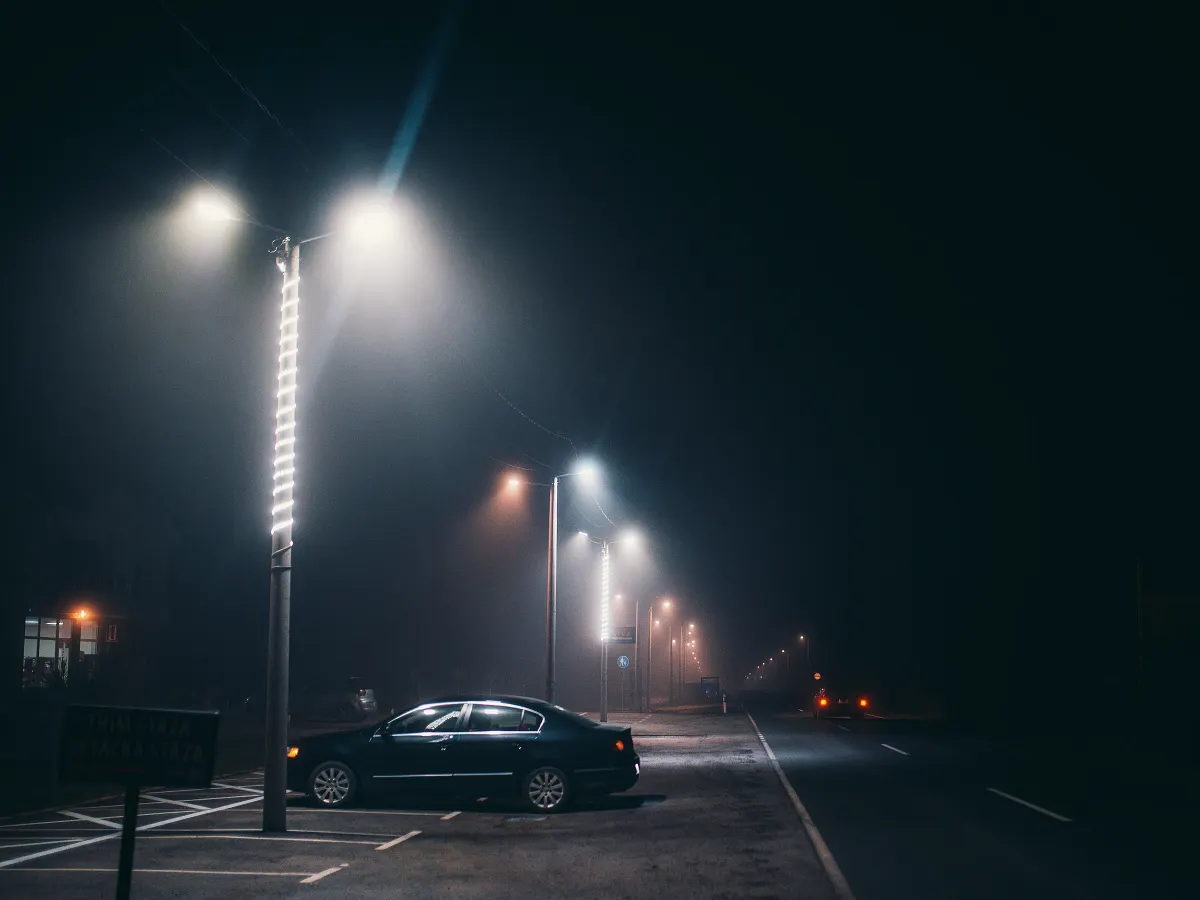 Straßenlaternen und ein geparktes Auto im nächtlichen Nebel